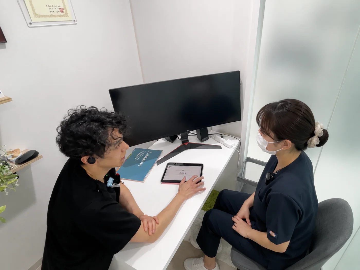 タブレットを見ながら歯科衛生士と症例を検討する坪川院長